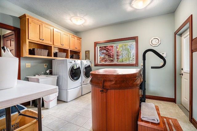 laundry area featuring cabinets, independent washer and dryer, a textured ceiling, and light tile patterned floors