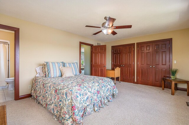 carpeted bedroom with two closets, ensuite bath, and ceiling fan