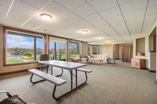 interior space featuring carpet floors, a drop ceiling, and a water view