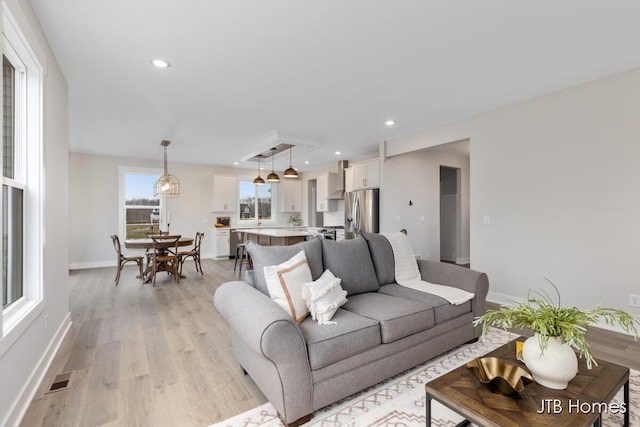 living room featuring baseboards, light wood finished floors, visible vents, and recessed lighting