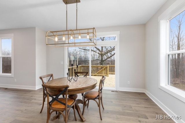 dining space with plenty of natural light, baseboards, and wood finished floors