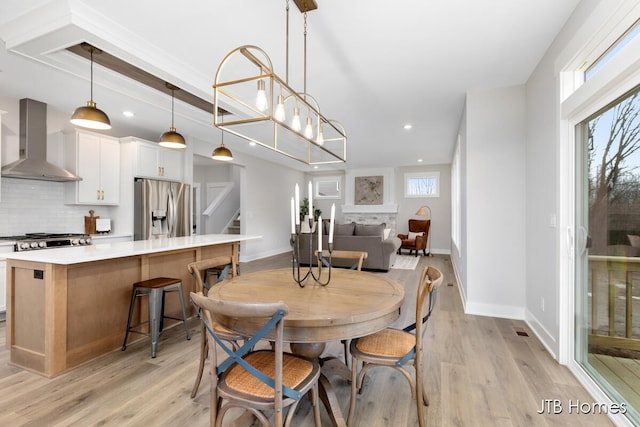 dining space with light wood-style floors, recessed lighting, baseboards, and stairs