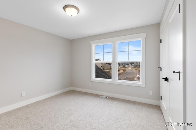 unfurnished room featuring light colored carpet, visible vents, and baseboards