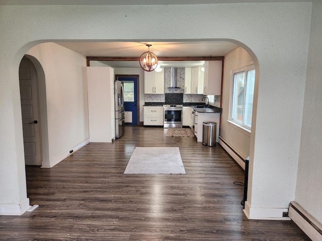 9318 School St, Lake, MI 48632 - kitchen with wall chimney exhaust hood, stainless steel appliances, baseboard heating, and dark countertops