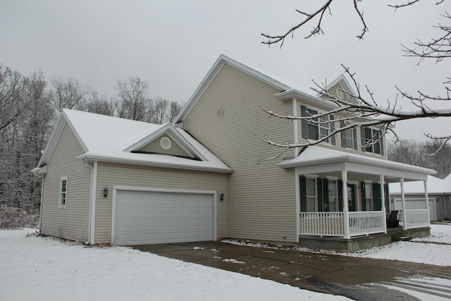 view of snowy exterior with covered porch and a garage