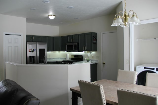 kitchen with kitchen peninsula, appliances with stainless steel finishes, sink, pendant lighting, and a notable chandelier