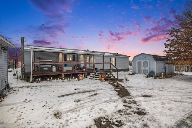 snow covered house featuring a shed and a deck