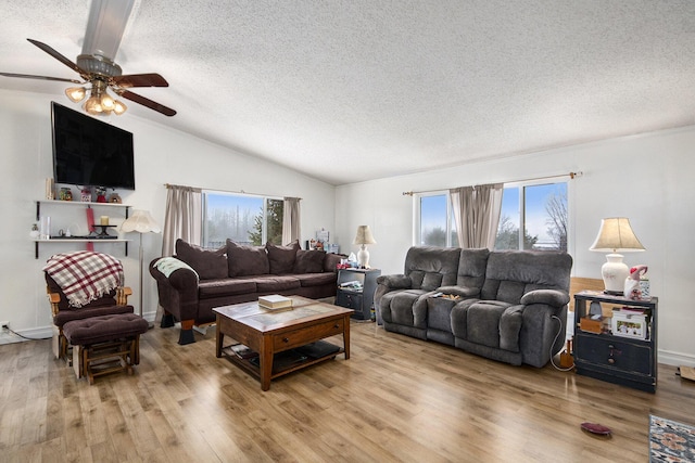 living room featuring a textured ceiling, ceiling fan, vaulted ceiling, and light wood-type flooring