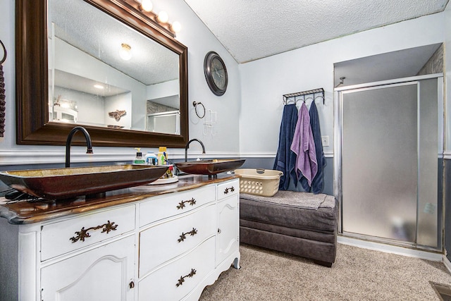 bathroom with vanity, an enclosed shower, and a textured ceiling