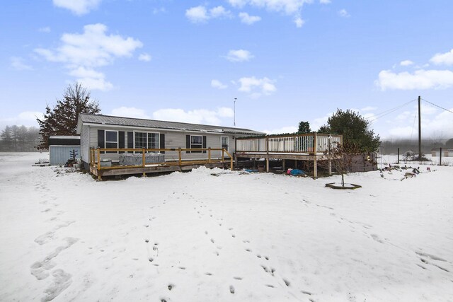 snow covered back of property featuring a wooden deck