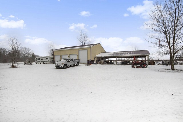 snow covered parking with a garage and a carport