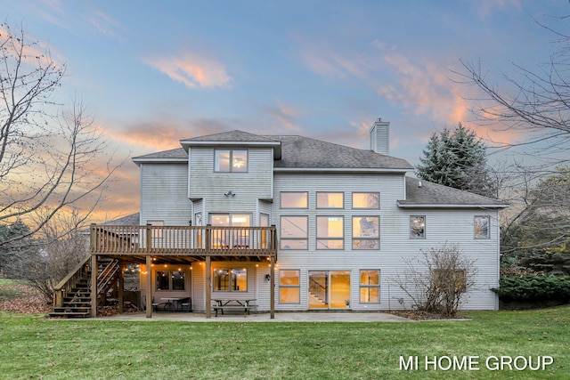 back house at dusk featuring a patio area, a yard, and a wooden deck