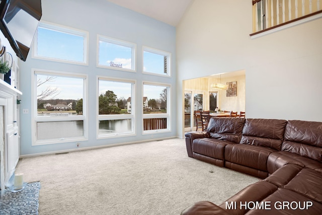 carpeted living room with a premium fireplace, a towering ceiling, and an inviting chandelier