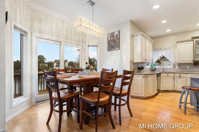 dining space with a chandelier, sink, and light hardwood / wood-style floors