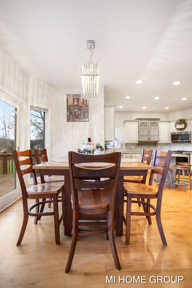 dining area with light wood-type flooring and a notable chandelier