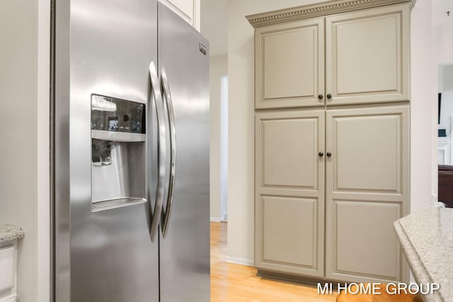 kitchen featuring cream cabinetry, stainless steel fridge with ice dispenser, light hardwood / wood-style flooring, and light stone counters