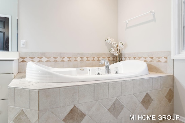 bathroom featuring tiled tub and vanity