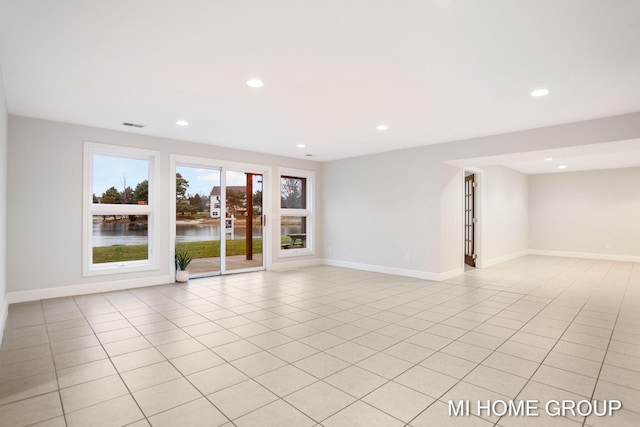 spare room with light tile patterned floors and a water view