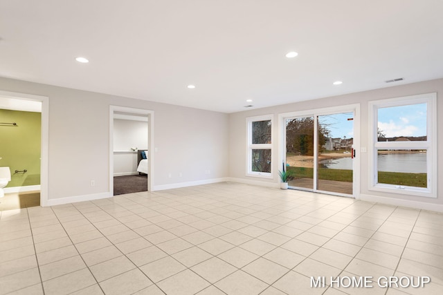 interior space featuring access to outside, ensuite bath, a water view, and light tile patterned flooring