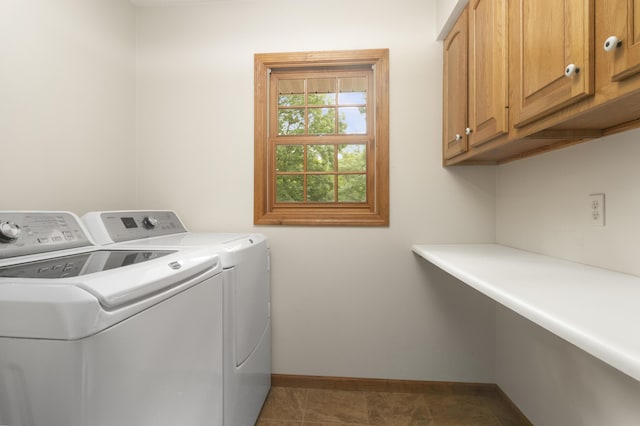 clothes washing area featuring cabinets, dark tile patterned flooring, and washing machine and clothes dryer