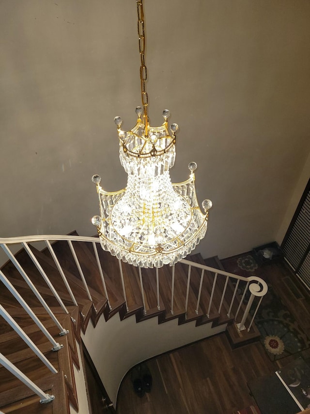 stairway with wood-type flooring and an inviting chandelier