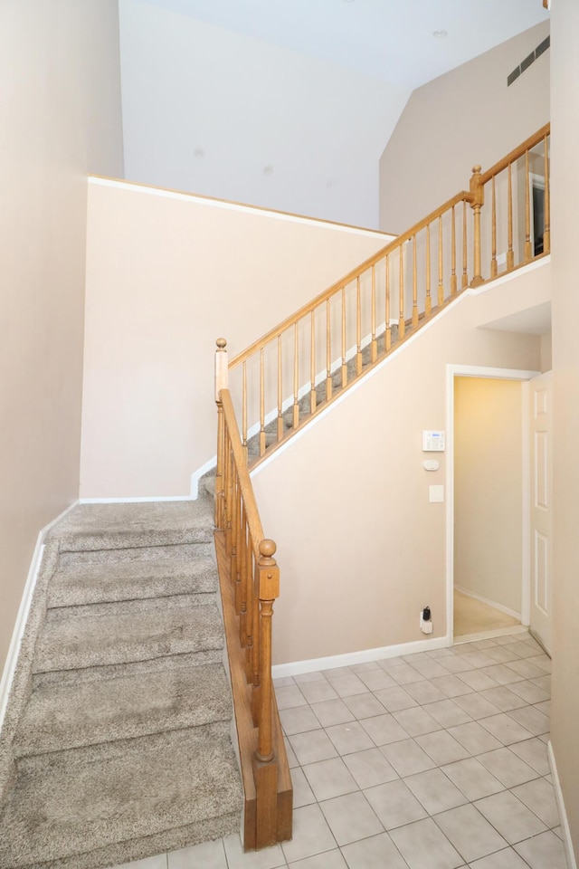 staircase featuring tile patterned floors and vaulted ceiling