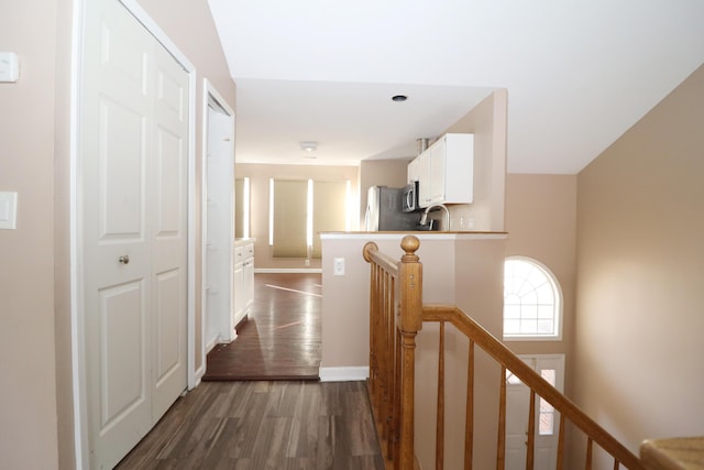 corridor with dark wood-type flooring and sink