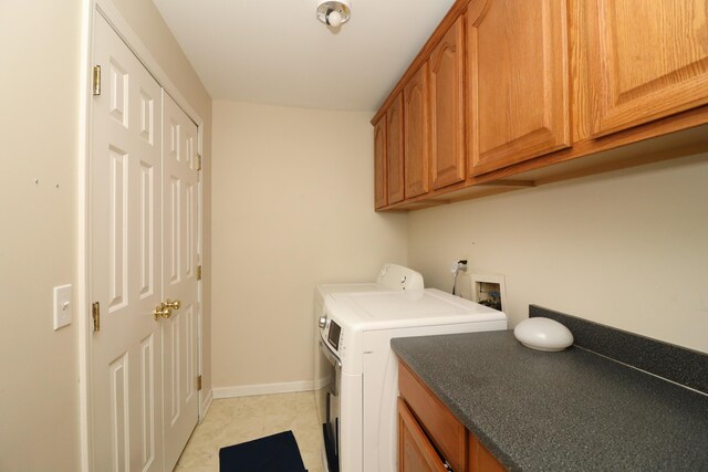 washroom with cabinets, light tile patterned floors, and washer and dryer