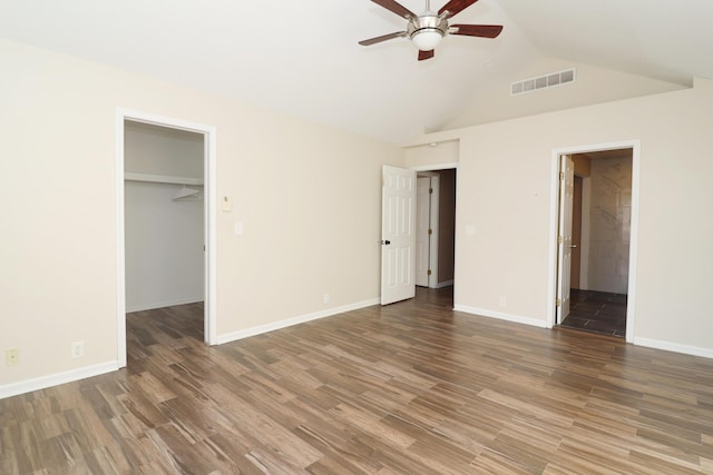 unfurnished bedroom featuring lofted ceiling, a walk in closet, ensuite bath, ceiling fan, and a closet