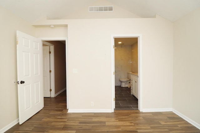 unfurnished bedroom featuring ensuite bathroom and dark wood-type flooring