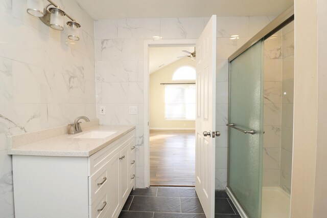 bathroom featuring tile patterned floors, vanity, ceiling fan, tile walls, and a shower with shower door