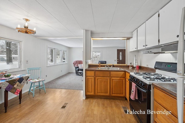 kitchen featuring gas stove, sink, light hardwood / wood-style flooring, an inviting chandelier, and white cabinetry