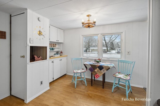 kitchen with white cabinets, a chandelier, and light wood-type flooring