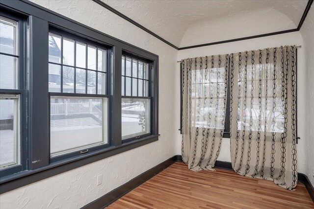 spare room featuring hardwood / wood-style flooring, a textured ceiling, and vaulted ceiling