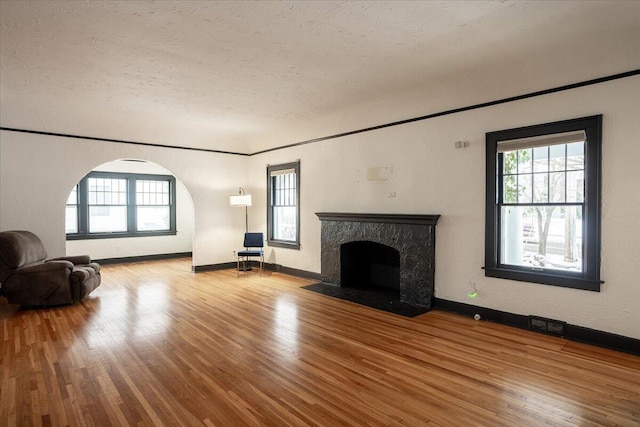 unfurnished living room featuring a textured ceiling, light hardwood / wood-style floors, and ornamental molding