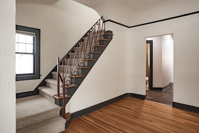 stairs with hardwood / wood-style floors and crown molding