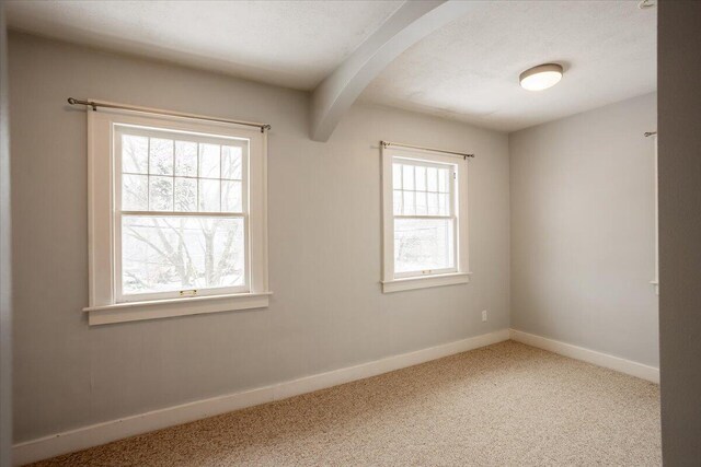 carpeted spare room featuring beam ceiling