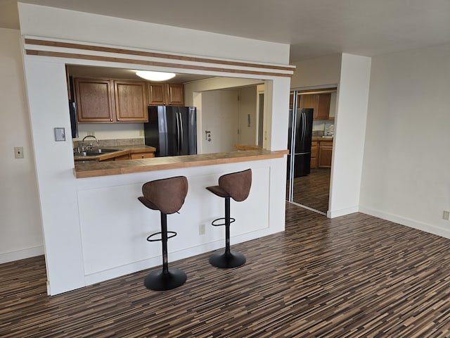 kitchen featuring black refrigerator, sink, kitchen peninsula, and a breakfast bar area