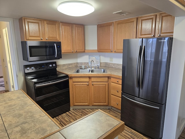 kitchen with appliances with stainless steel finishes, tile counters, and sink