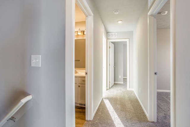 hall featuring light colored carpet and sink