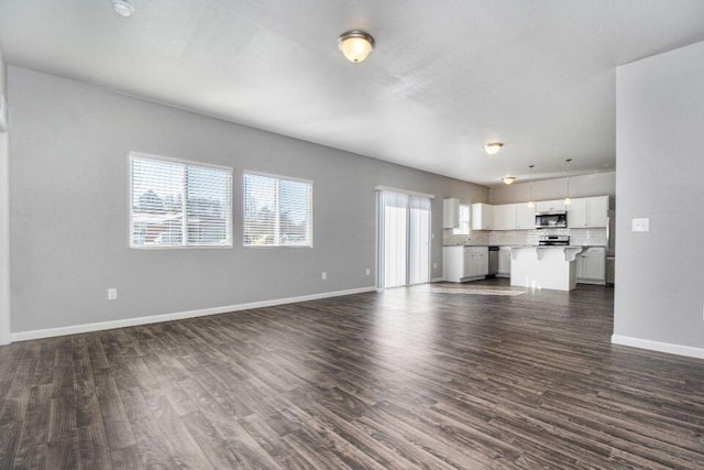 unfurnished living room with dark wood-type flooring and a wealth of natural light