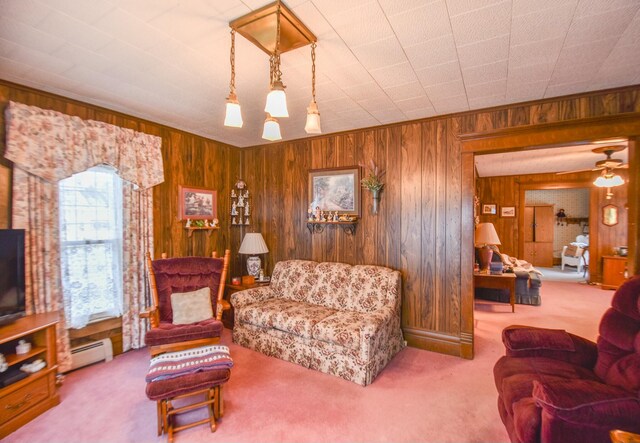 living room featuring wood walls, carpet floors, and baseboard heating