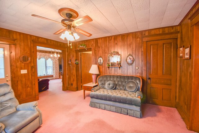 carpeted living room featuring ceiling fan and wood walls