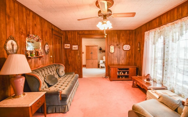 carpeted living room featuring wooden walls and ceiling fan