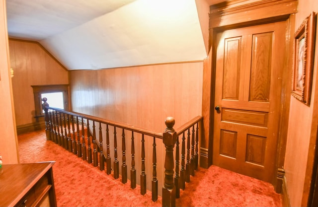 interior space featuring light carpet, wooden walls, and lofted ceiling