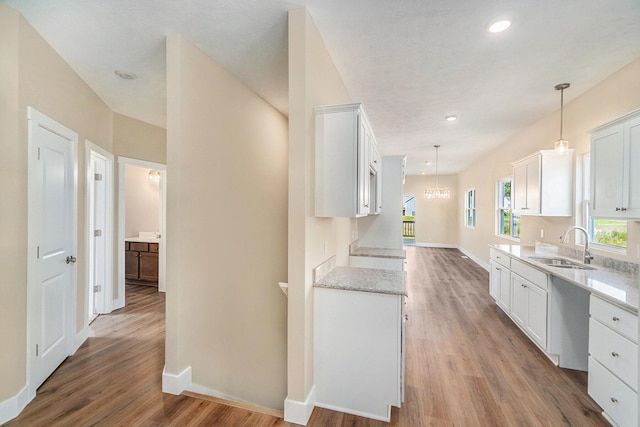 kitchen featuring decorative light fixtures, sink, and white cabinets