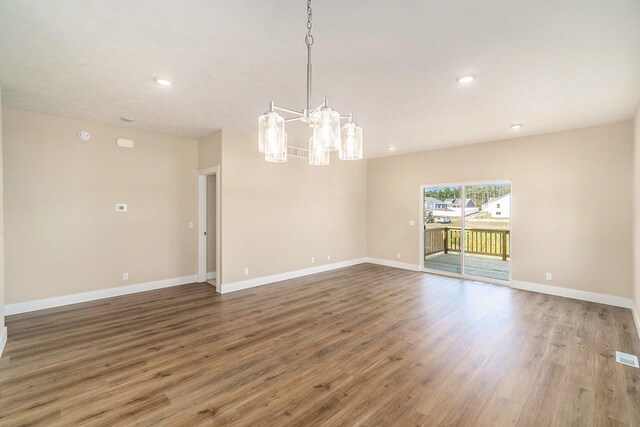 unfurnished room featuring hardwood / wood-style floors and a chandelier