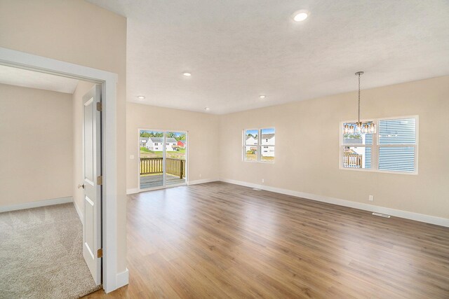 spare room featuring a chandelier and light wood-type flooring