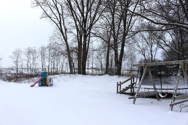 snowy yard with a playground and a trampoline