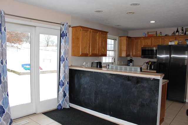 kitchen featuring stainless steel appliances, light tile patterned flooring, and kitchen peninsula